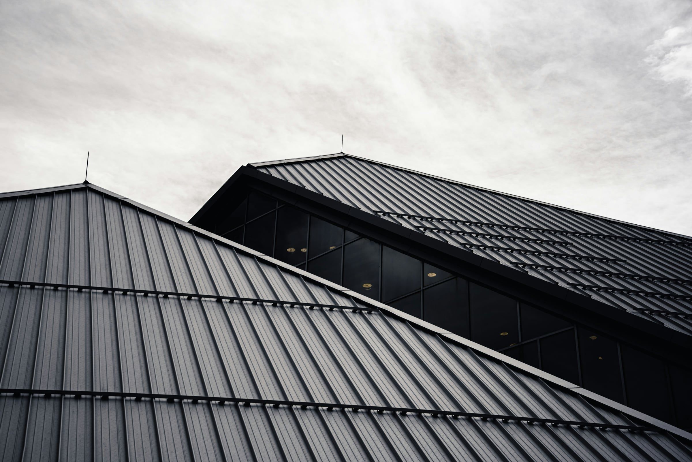 Dark gray standing-seam metal roof panels with raised vertical seams running from ridge to eave